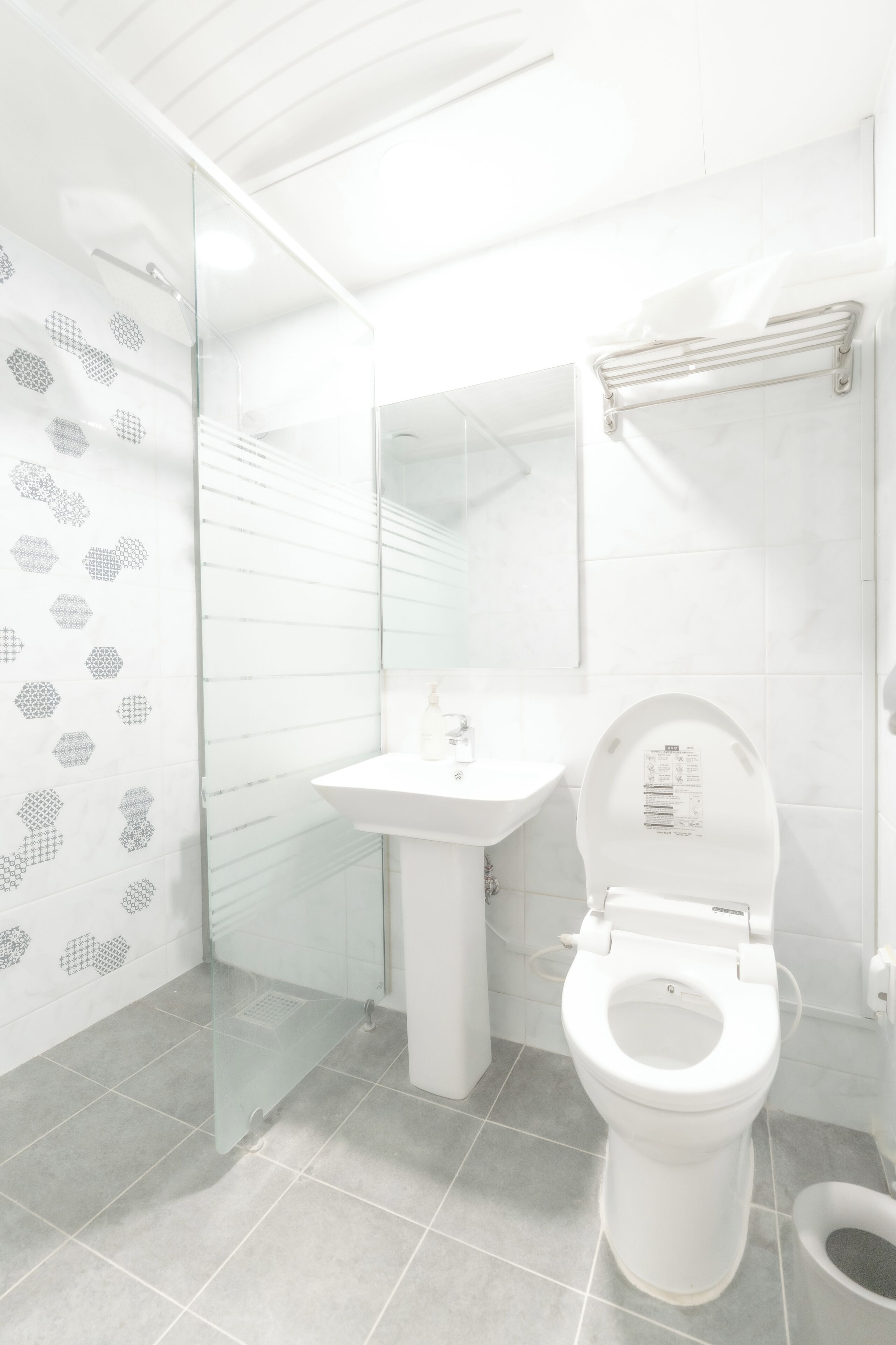Une salle de bain moderne équipée de toilettes, d’un lavabo et d’une douche à parois de verre.