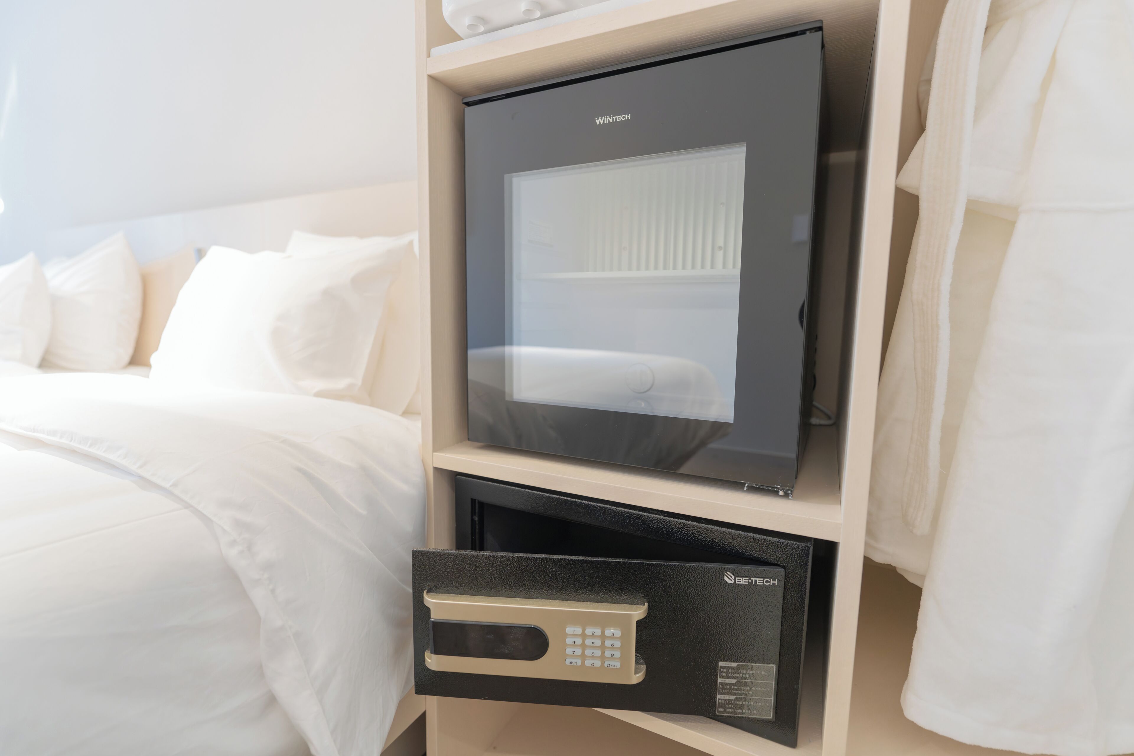 Una habitación de hotel con cama, minibar y caja fuerte.