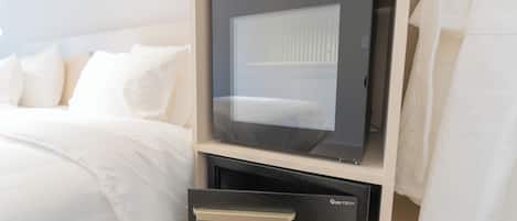 Una habitación de hotel con cama, minibar y caja fuerte.