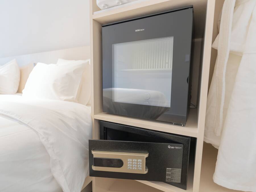 Una habitación de hotel con cama, minibar y caja fuerte.