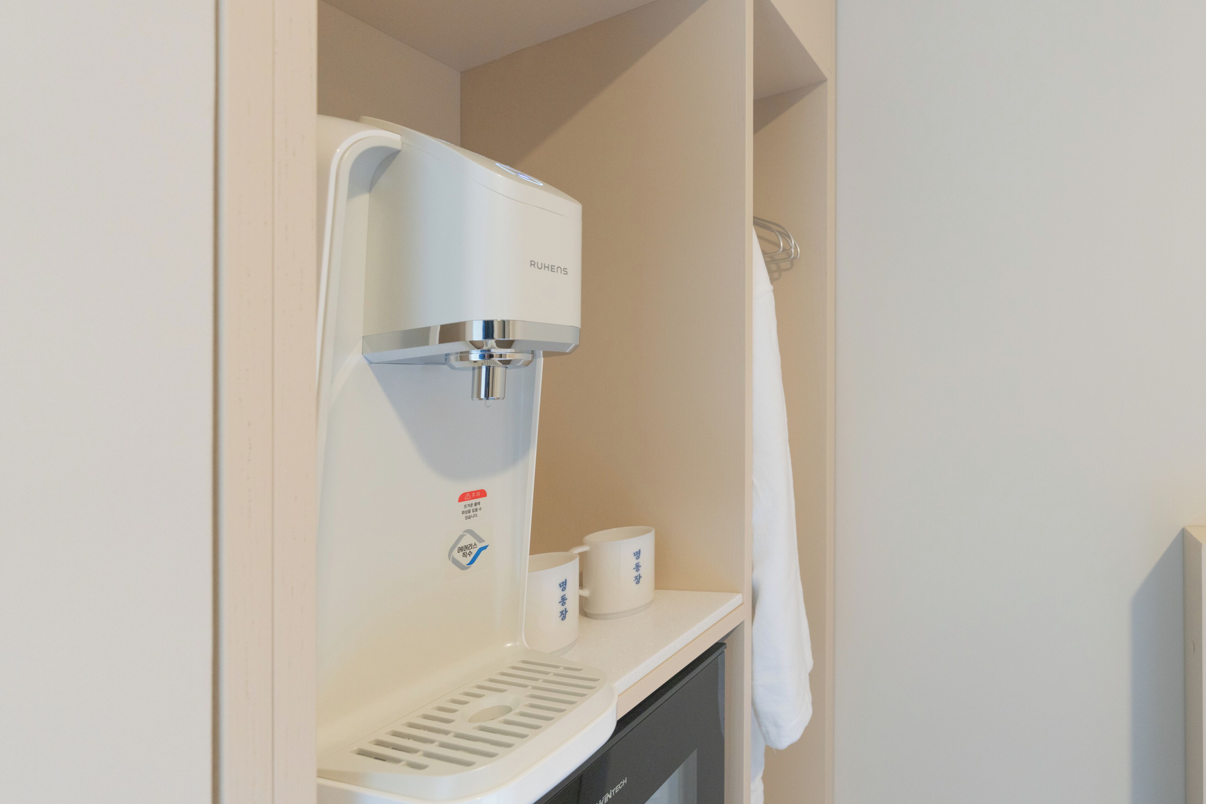 Una cafetera con un portaluces y un perchero en un baño.