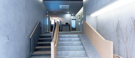 Un interior moderno con una escalera, paredes grises y barandilla de madera.