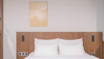 A hotel room with a wooden headboard, white bedding, and a wall-mounted artwork.