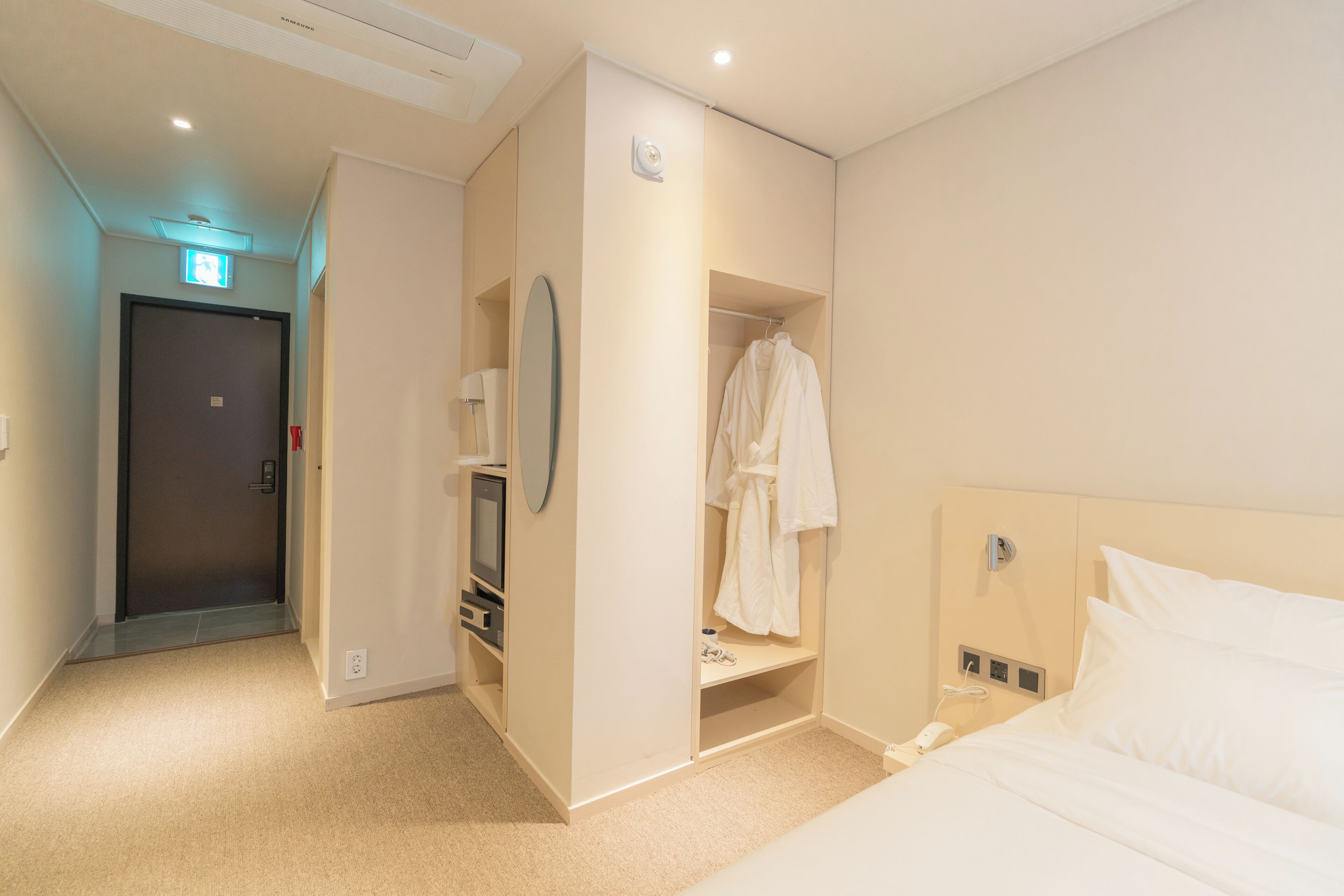 A hotel room with a bed, a wardrobe, a mirror, and a television.