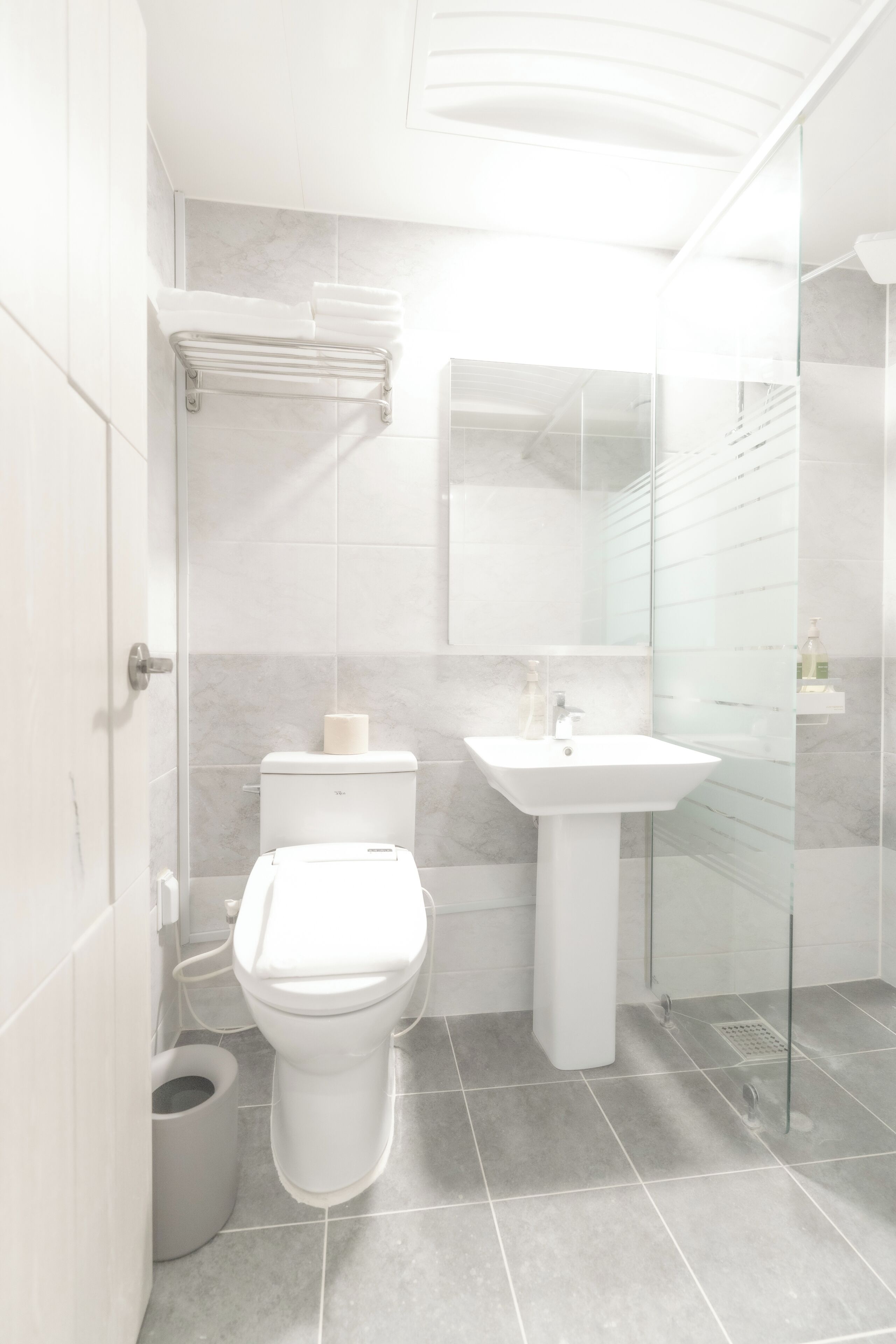 Une salle de bain moderne équipée de toilettes, d’un lavabo et d’une douche à parois en verre.
