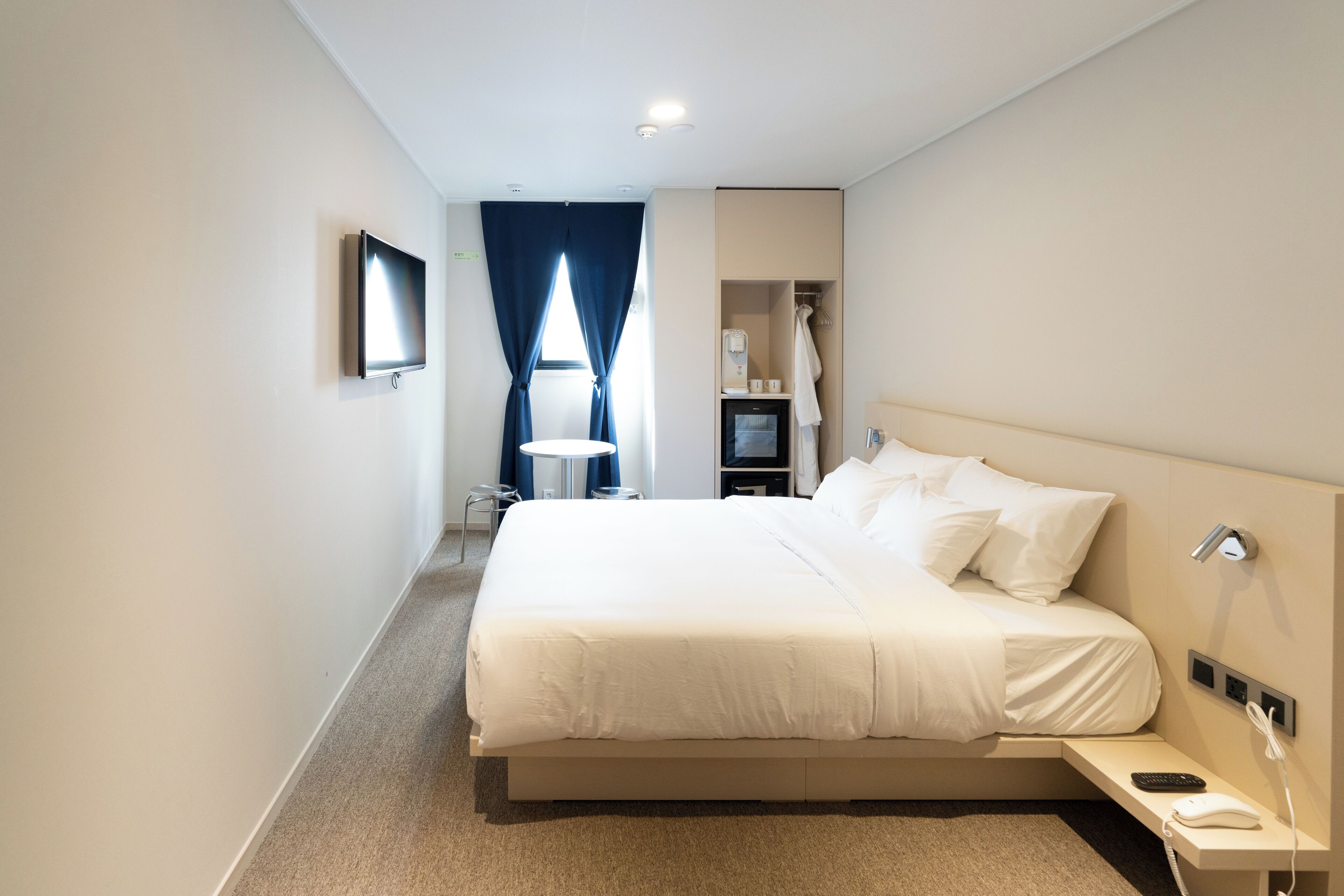 A hotel room with a large bed, bedside tables, a TV, and a bathroom with a shower and toilet.