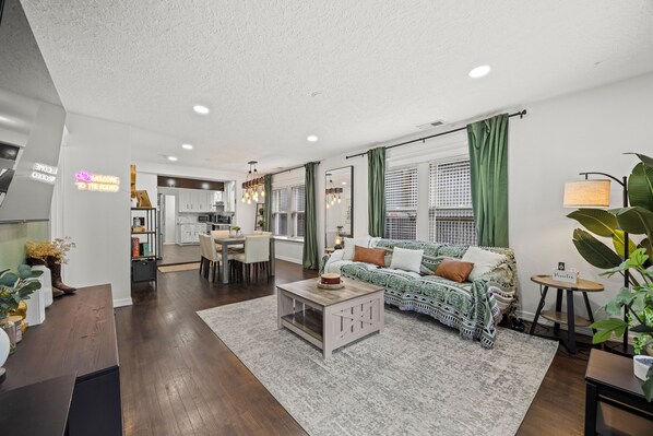 A modern living room with a sofa, coffee table, and dining area.