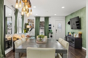 A dining area with a wooden table, cushioned chairs, and a hanging light fixture.