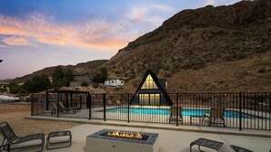 A poolside area with a fire pit, lounge chairs, and a fenced enclosure. - Hurricane Oasis with Private Pool & Gorgeous Views (Hurricane)