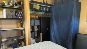 Ein Schlafzimmer mit einem Bett, einem Kleiderschrank und einem Regal mit Büchern und einem dekorativen Gegenstand.