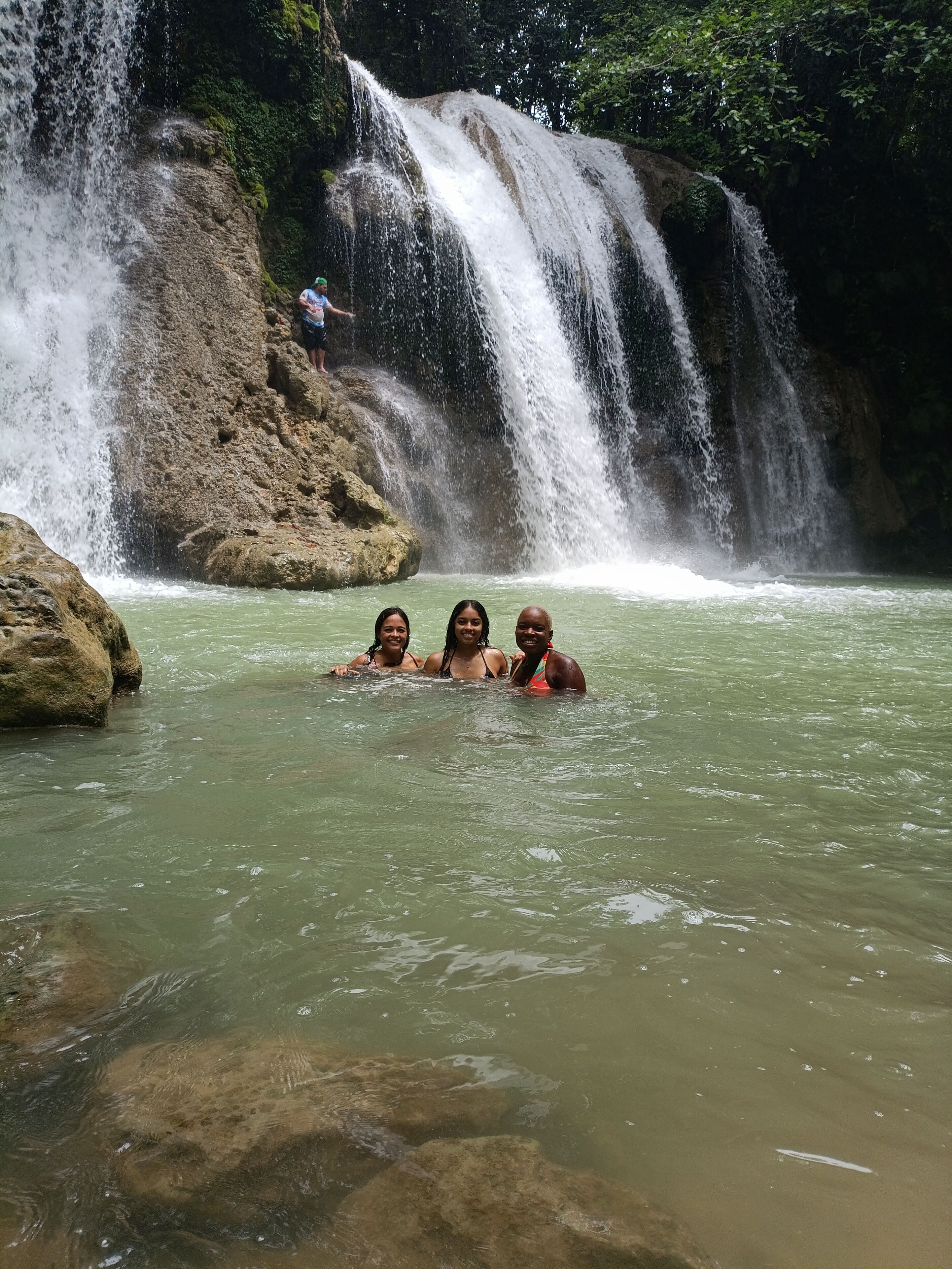 A waterfall with three people in the water.