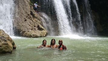 A waterfall with three people in the water.