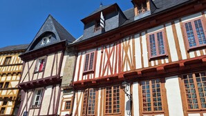 Ein traditionelles Fachwerkhäuschen mit einem steilen Satteldach, zahlreichen Fenstern mit Holzrahmen und einem sichtbaren Schornstein.