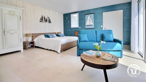 Ein modernes Schlafzimmer mit einem Bett, einem blauen Sofa und einem runden Couchtisch.