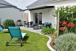A patio with outdoor furniture, a covered area, and a garden with various plants and flowers.
