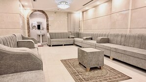 A modern living room with a sectional sofa, a coffee table, and a patterned rug. - Golden Hospitality Hotel (Makkah)