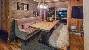 A cozy room with a wooden table, a pink sofa, a fluffy bench, and a fireplace. - 3 bedroom nice home in Tuddal (Tuddal)