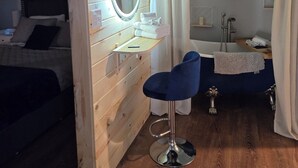 Une pièce comprenant un lit, une coiffeuse avec un miroir, une chaise bleue et une baignoire.