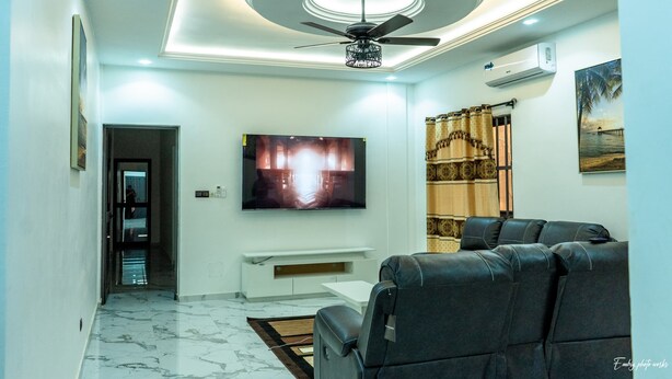 Un soggiorno moderno con una televisione a schermo piatto, un ventilatore a soffitto e un divano.