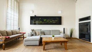 A living room with a sofa, a coffee table, a fireplace, and a large aquarium on the wall.