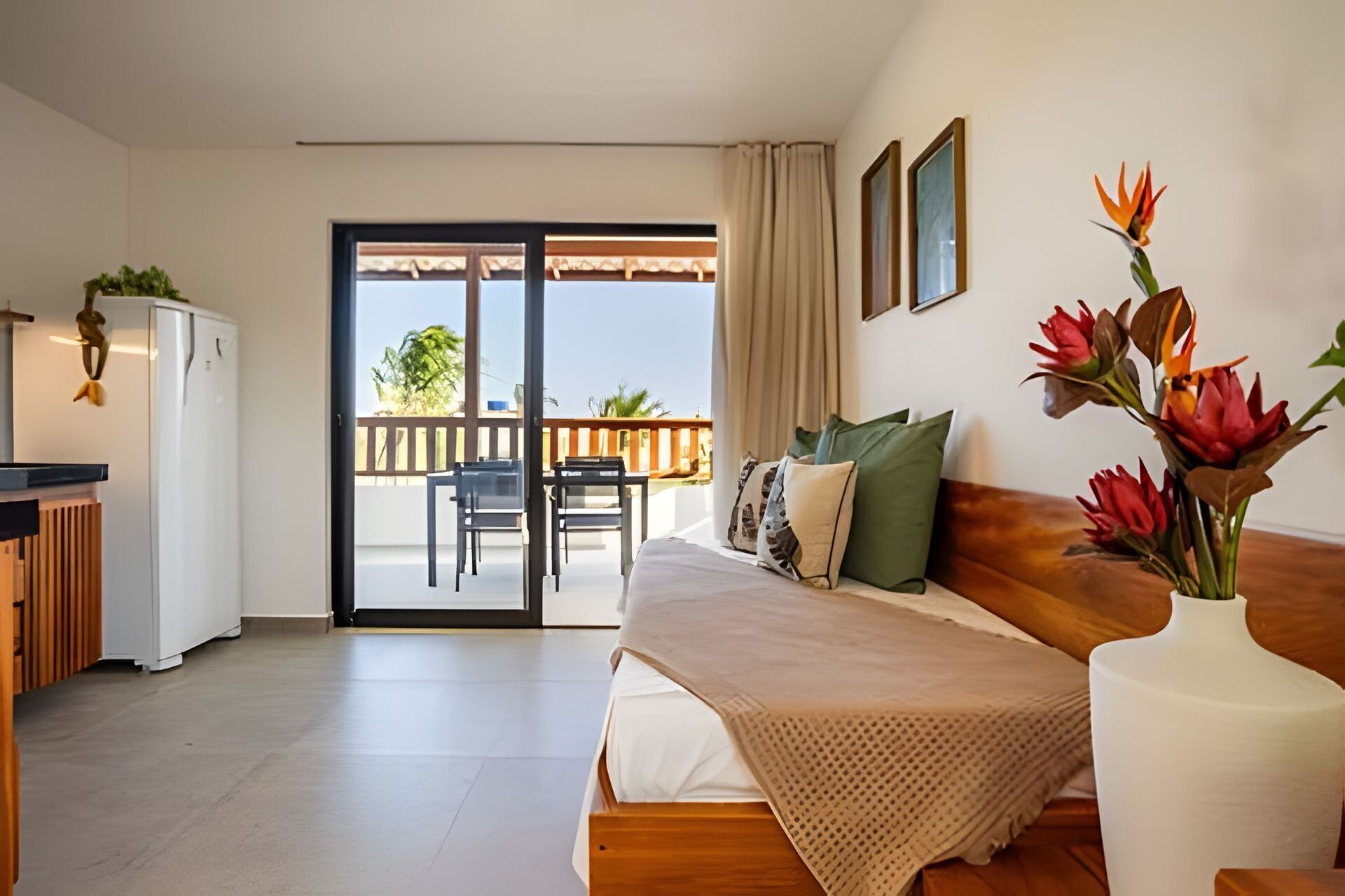 A bedroom with a bed, a desk, a chair, a balcony, and a view of the outdoors.