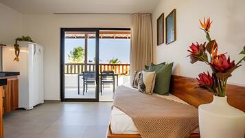 A bedroom with a bed, a desk, a chair, a balcony, and a view of the outdoors.