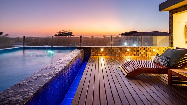 A rooftop pool area with a wooden deck, a lounge chair, and a view of the sunset. - Arara House (Jijoca de Jericoacoara)