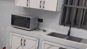 A kitchen with white marble cabinets, a microwave, a sink, and a black stove.