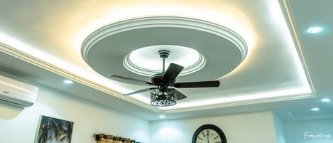 A ceiling with a central circular light fixture and a ceiling fan.