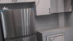 A kitchen with a stainless steel refrigerator, white cabinets, and a marble backsplash.