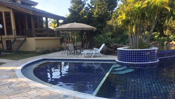 Una piscina amb terrassa de pedra, gandules i zona de porxo coberta.