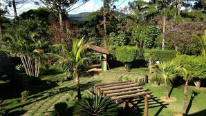 Jardí amb una pèrgola de fusta, camins de pedra i diverses plantes tropicals.