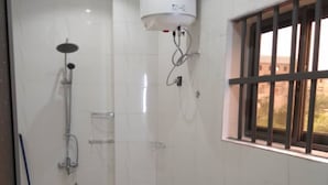 A bathroom with a toilet, a shower, and a window with bars.