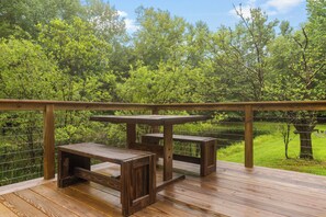 Enjoy a serene view of the lush landscape from this outdoor deck with a table and two benches.
