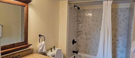 Ein Badezimmer mit Dusche, Waschbecken, Spiegel und Handtuchhalter.