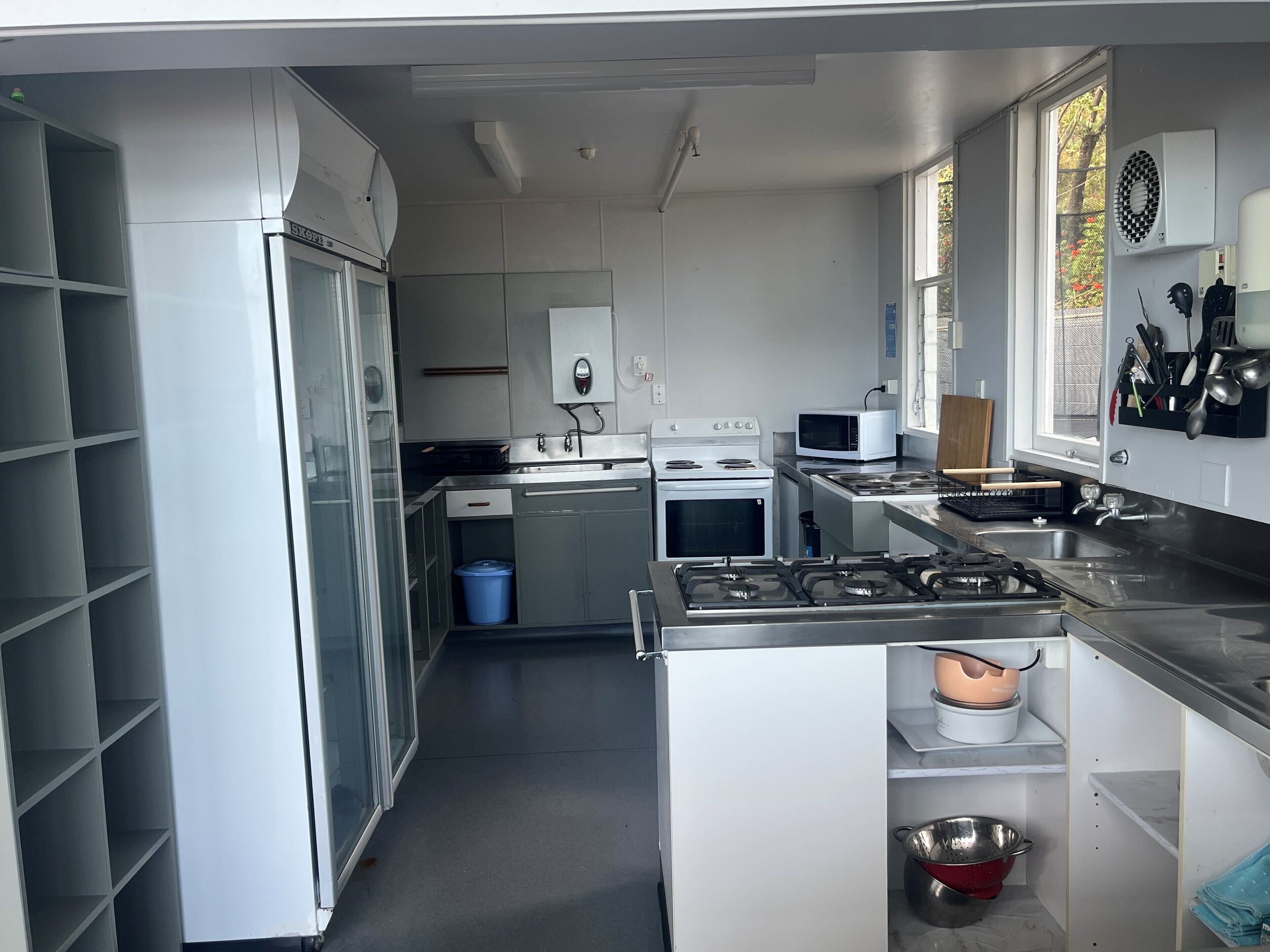 Una cocina moderna con gabinetes blancos, estufa a gas, microondas y horno empotrado.