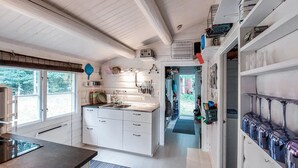 A modern kitchen with white cabinets, a central island, and a view to the outdoors.