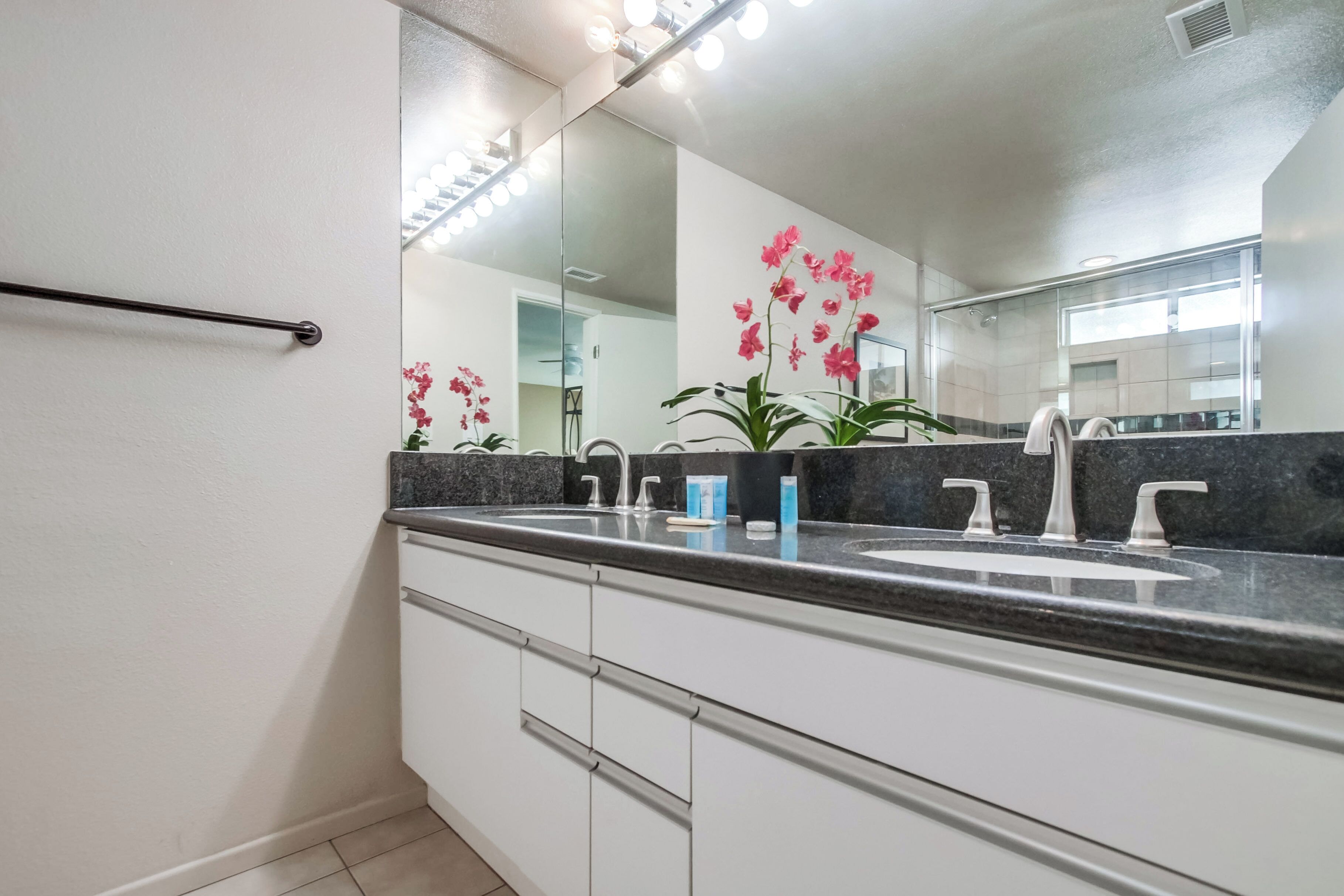 A modern bathroom with a large mirror, two sinks, and a towel rack.