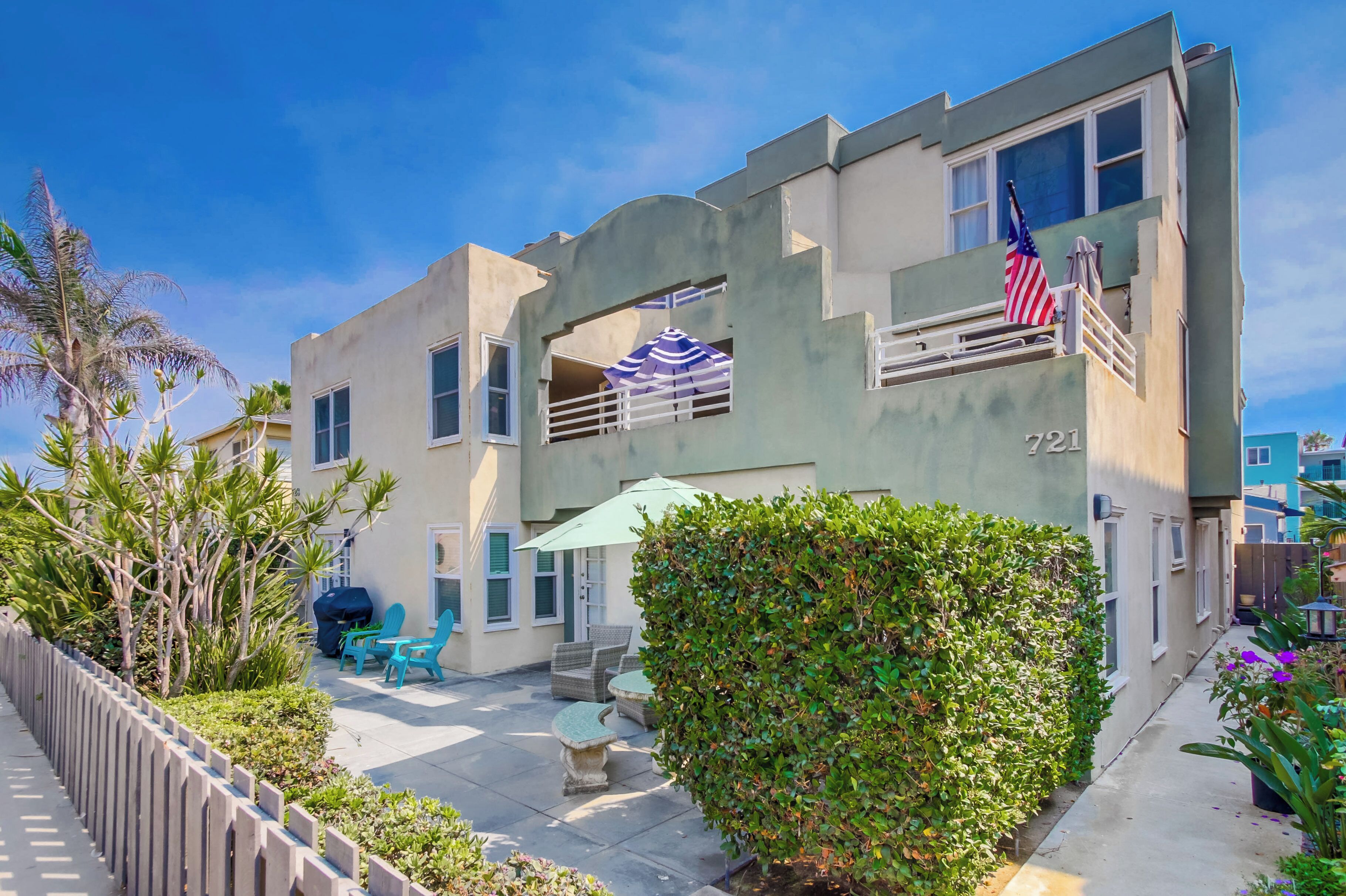 A two-story building with a balcony, a flag, and outdoor seating.