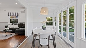 A modern living room with a grey sofa, a round coffee table, and a dining area with a white table and chairs. - Charming Cottage by the Water Pet Friendly WoyWoy (Woy Woy)