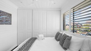A bedroom with a bed, a window with blinds, a door, and a wall-mounted artwork. - Dream View Steps from the Beach (Coogee)