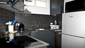 A modern kitchen with a black countertop, stainless steel appliances, and a black and white backsplash.