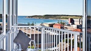 A balcony with a view of the sea and buildings.