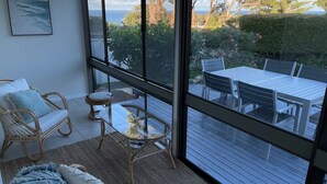 Un balcon avec vue sur la mer, aménagé avec des fauteuils en osier, une petite table et un canapé.