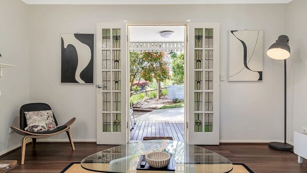 A modern interior with a glass table, a chair with a floral cushion, and artwork on the walls. - Katoomba Cottage Escape Near the Three Sisters (Katoomba)