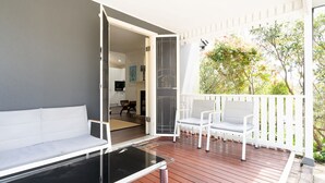 A balcony with a white sofa, two white chairs, and a glass table. - Katoomba Cottage Escape Near the Three Sisters (Katoomba)