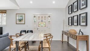 A dining area with a marble table, wooden chairs, and a wooden sideboard with framed pictures. - Katoomba Cottage Escape Near the Three Sisters (Katoomba)
