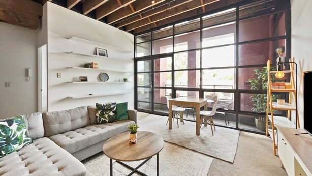 A modern living room with a sofa, coffee table, and dining area. - Brick & Beam New York Style Loft in Chippendale (Chippendale)