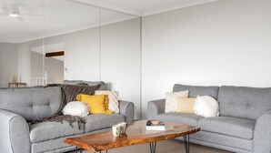 A modern living room with two grey sofas, a wooden coffee table, and various cushions. - Mountain View Hideout with Stargazing Telescope (Wentworth Falls)