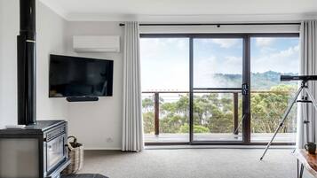 A modern living room with a TV, fireplace, and balcony with a scenic view.